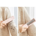 Load image into Gallery viewer, Person using a pink pet hair remover on a beige sweater with hair collected on it.