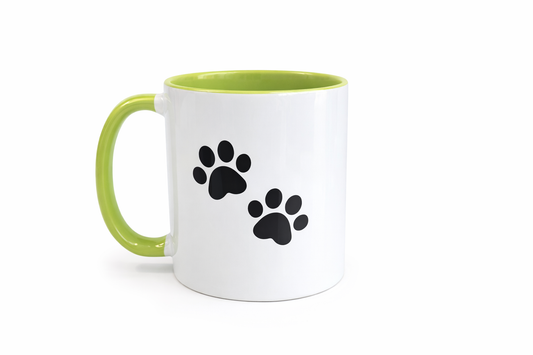White mug with green handle featuring black paw prints on a white background