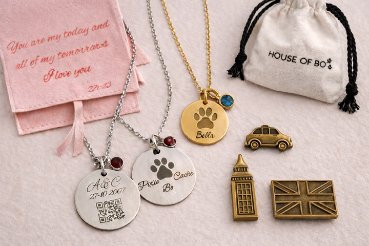 Collection of personalized necklaces and pins with engraved details on a light surface.